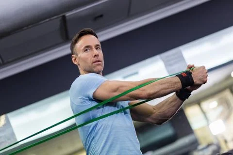 Man doing side-to-side chops exercise with elastic band at the gym. Stock Photos