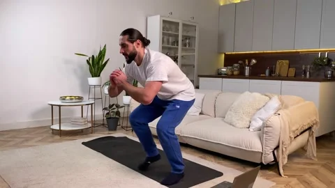 Man doing Side Step Squat exercise watching tutorial on computer home Video stock 229567849
