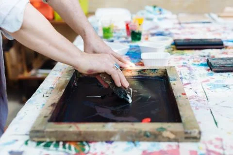 Man doing silk screen print in creative studio, mid section, close-up Foto stock