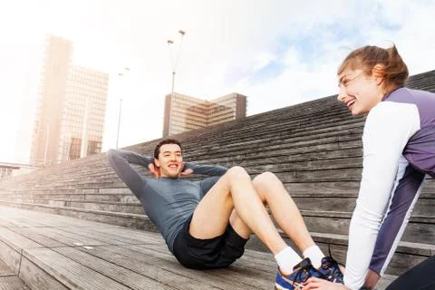 Man doing sit-ups exercises with female instructor Stock Photos