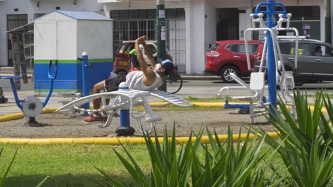 A man doing sit-ups in a mini gym in a park in the day wearing mask 스톡 동영상 149896736