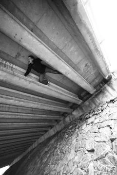 Man doing some parkour under a bridge structure Stock Photos