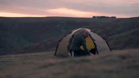 A man doing something inside his wild camping tent in the hills 스톡 동영상 346639368