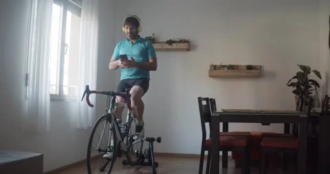 Man doing spining in his living room while chatting with a smartphone Stock Footage 145908096