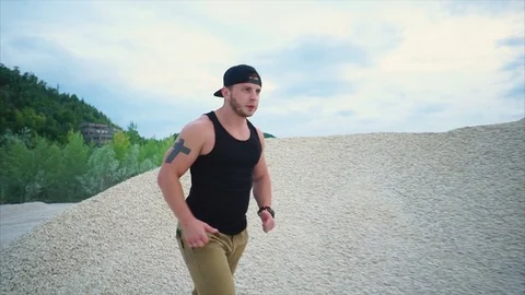 Man doing sports at the quarry. He running among gravel hills Stock Footage