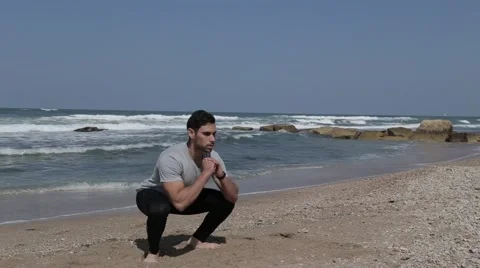 Man doing squat exercise on the beach Stock Footage 61461685