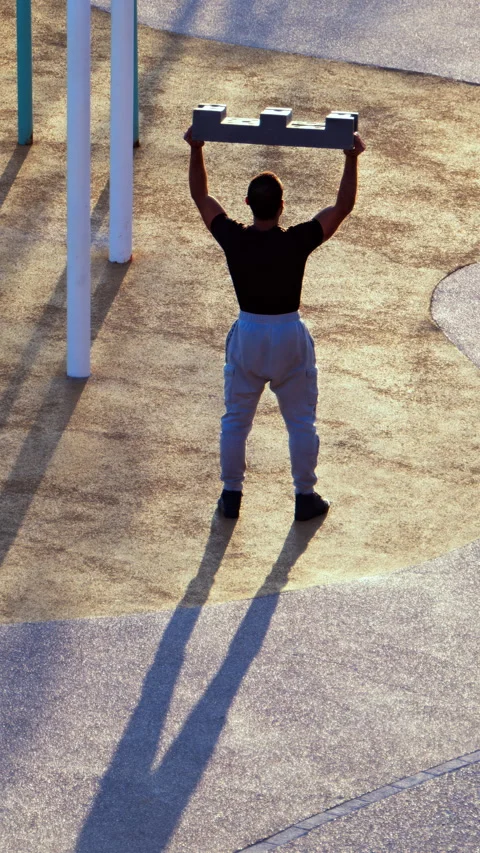 Man doing squats with a construction block on the beach. Vertical Stock Footage 305876123