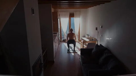 Man doing squats at home with dog in sunlight lifestyle moment Stock Footage 332558167