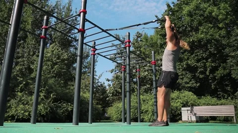 Man doing squats on playground among the trees, total body resistance exercise 動画素材 139398202