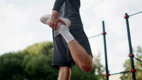 Man doing a standing leg stretch on an outside gym. Man in black athletic c.. Stock-Footage 341729716