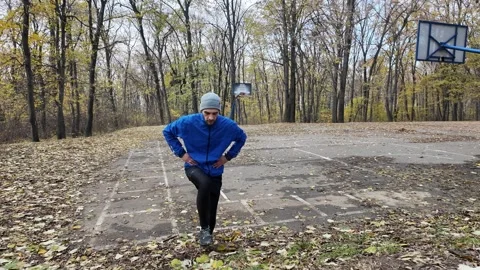Man doing step-up exercise on outdoor platform in autumn park, training legs and Stock Footage 318168041