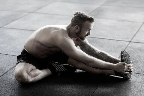 Man Doing Stretching Exercise In Gym Foto stock