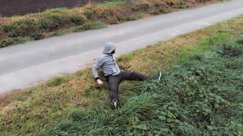 Man is doing stretching exercises on green grass near road. Footage HD. Stock Footage 147742341