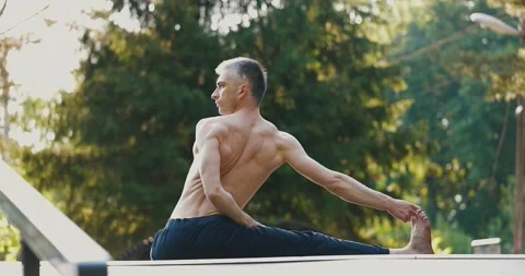 Man doing stretching while practicing yoga alone in city park.Athlete performing Stock Footage 158456662