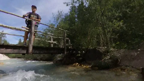 A Man doing Trek is on a wooden bridge on a creek 360effect Stock Footage 114074969