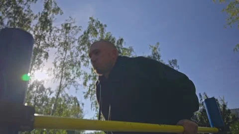 Man doing triceps dip exercise on parallel bars with extra weights at open gym. Video stock 285616700