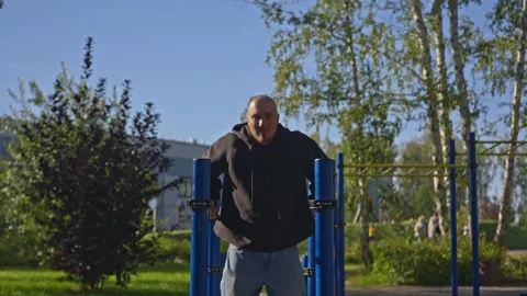 Man doing triceps dip exercise on parallel bars with extra weights at open gym. Video stock 285616791