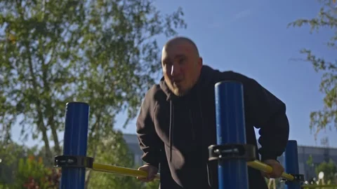 Man doing triceps dip exercise on parallel bars with extra weights at open gym. Video stock 285616894