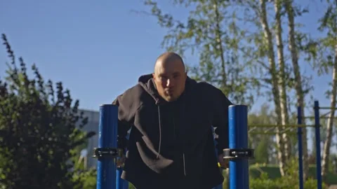 Man doing triceps dip exercise on parallel bars with extra weights at open gym. Video stock 285616895