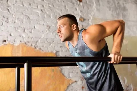Man doing triceps dip on parallel bars in gym 写真素材
