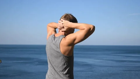 Man doing a warm-up exercise on the ocean. Fresh air and a healthy lifestyle 動画素材 96489189