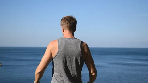Man doing a warm-up exercise on the ocean. Fresh air and a healthy lifestyle 動画素材 96489222