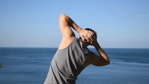 Man doing a warm-up exercise on the ocean. Fresh air and a healthy lifestyle 動画素材 96489231