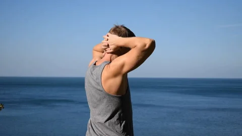 Man doing a warm-up exercise on the ocean. Fresh air and a healthy lifestyle 動画素材 96489264