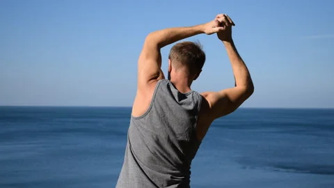 Man doing a warm-up exercise on the ocean. Fresh air and a healthy lifestyle 動画素材 96489270