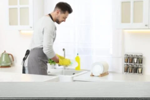 Man doing washing up in kitchen, focus on empty grey stone table Stock Photos