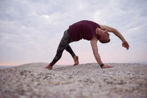 Man doing the wild thing pose on rocks at dusk Stock Photos