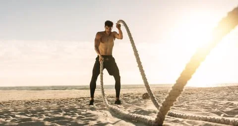 Man doing workout using battling ropes at the beach Foto stock