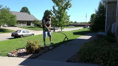 Man doing yard work with weed eater / trimmer / edger Stock Footage 12017899