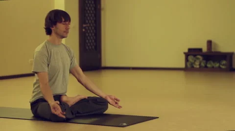 Man doing yoga asanas in the hall, then gets up, turns off the mat and goes Stock-Footage 67651755