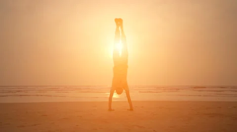 Man doing yoga during sunset on the beach Stock Footage 61207837
