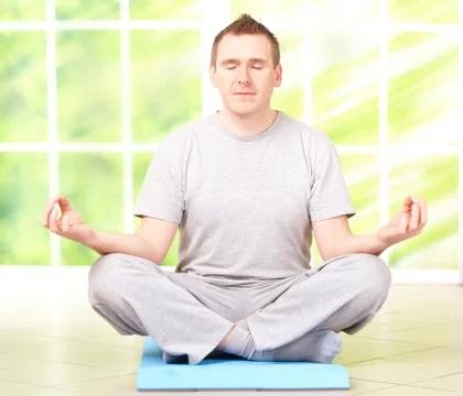 Man doing yoga exercise on mat Stock Photos