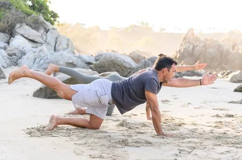 Man doing yoga exercise on sandy beach Stock Photos