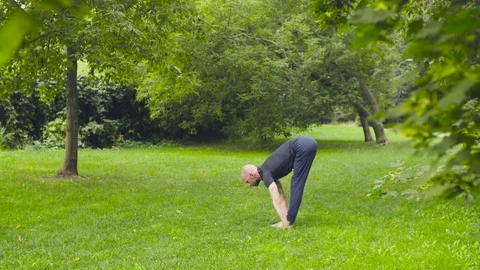 A man doing yoga exercises in the park Stock Footage
