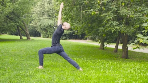 A man doing yoga exercises in the park Stock Footage 79396157