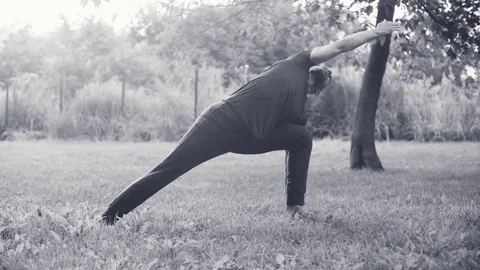 A man doing yoga exercises in the park Stock Footage