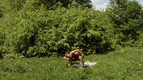 Man doing yoga in green grass in a mountain forest overall plan Stock Footage 77756272