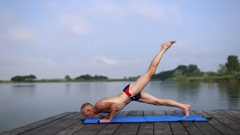 A man doing yoga by the lake Stock Footage 75810912