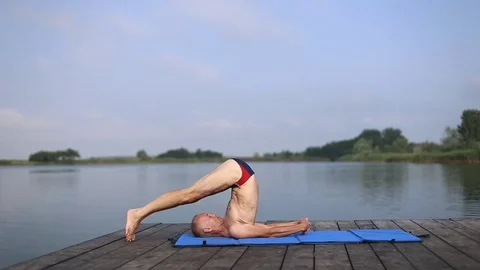 A man doing yoga by the lake Stock Footage 76894729