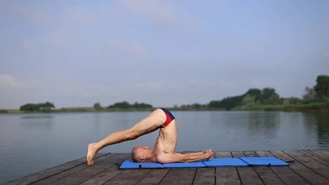 A man doing yoga by the lake Stock Footage 78191668