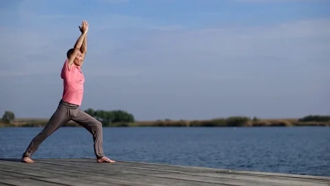 A man doing yoga by the lake Stock Footage 80997873