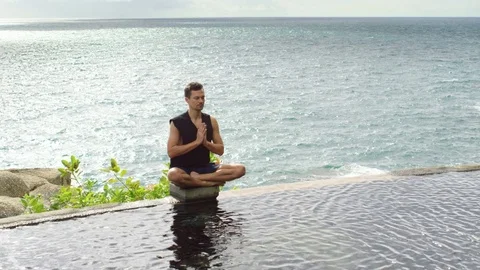 Man doing yoga near infinity pool against sea Stock-Footage 74778933