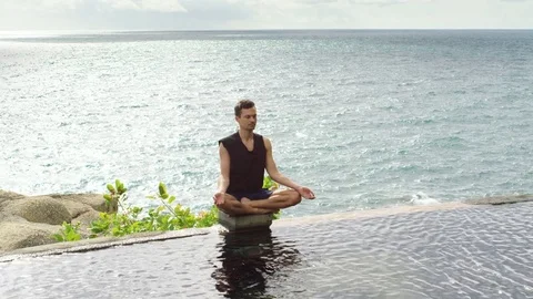 Man doing yoga near infinity pool against sea Stock Footage 75290965