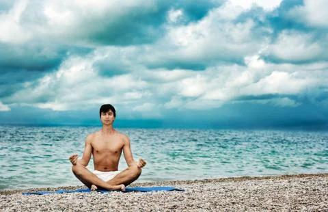 Man Doing Yoga near the Sea Stock Photos