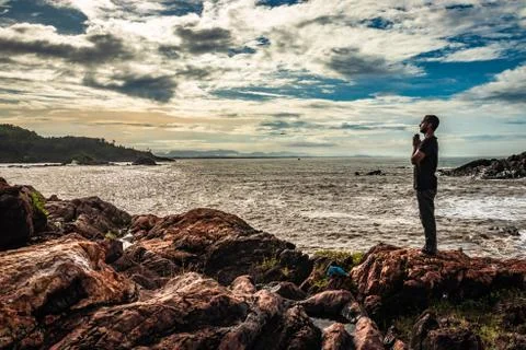 Man doing yoga practice at rock at sea shore at morning from flat angle 스톡 사진