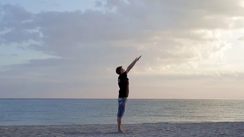 A man doing yoga practice at the sunset on the seaside Stock Footage 91144448